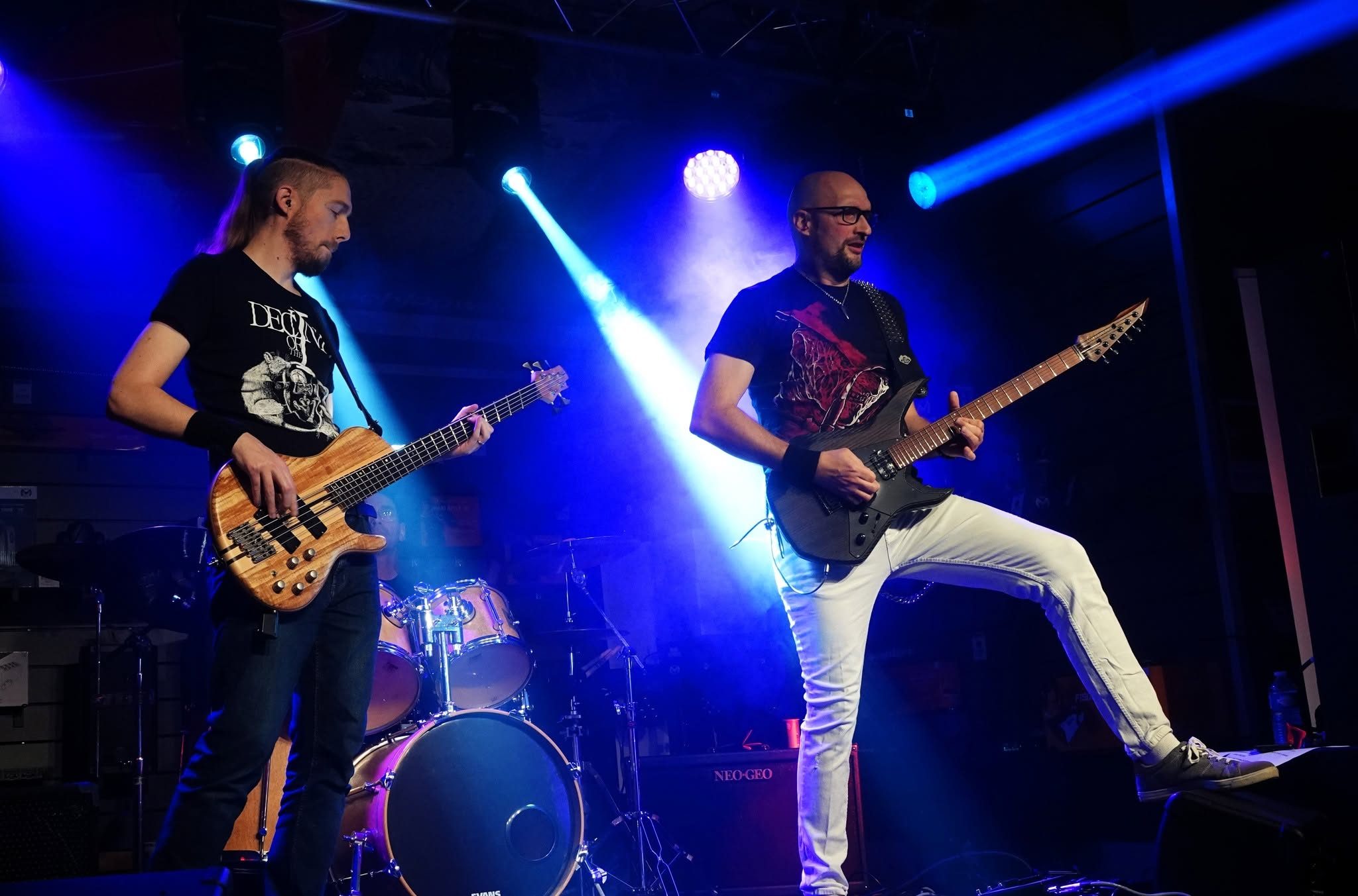 Le bassiste et le guitariste de 83FM sous des lumières bleues