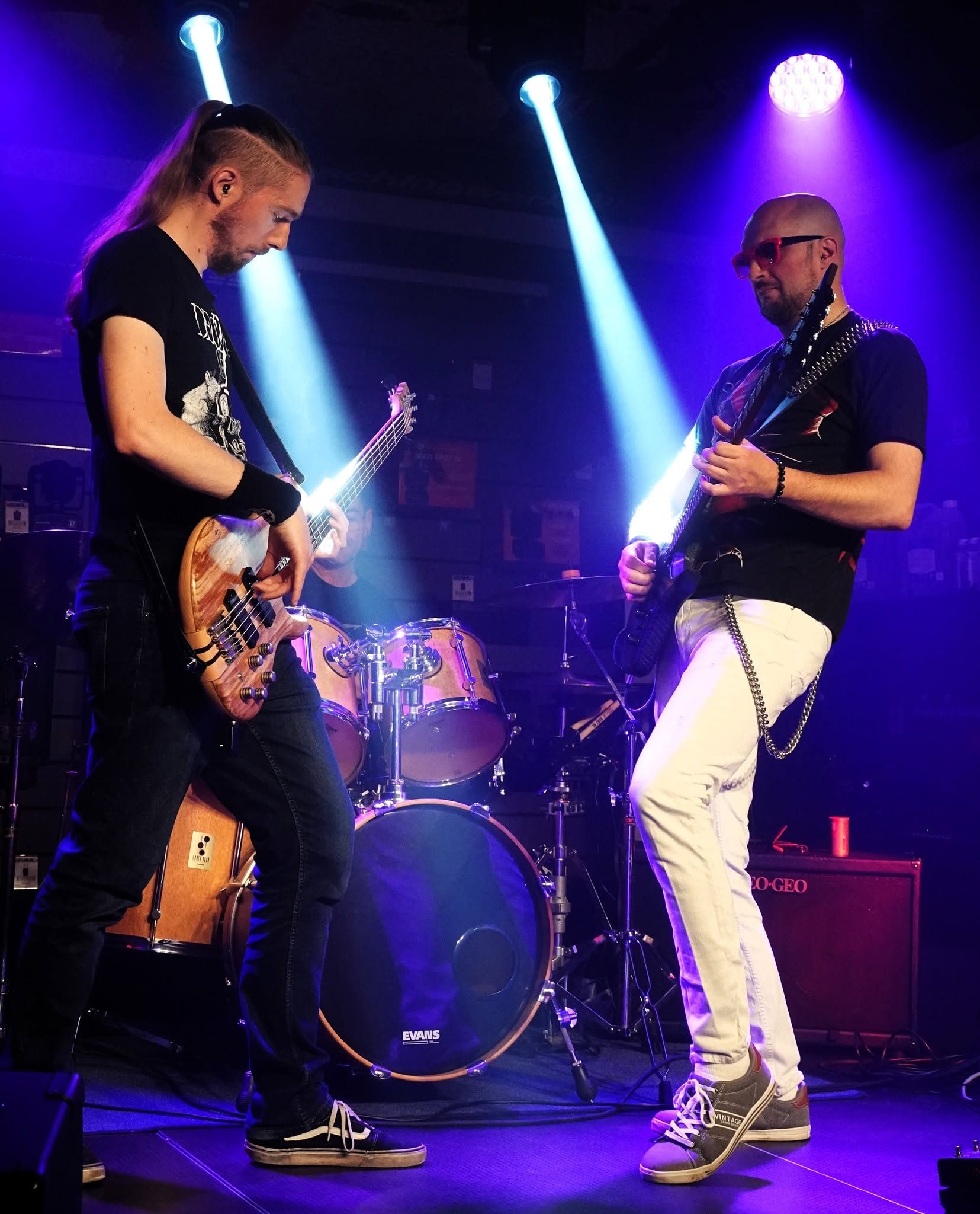 Le bassiste et le guitariste de 83FM face à face sous des faisceaux bleus