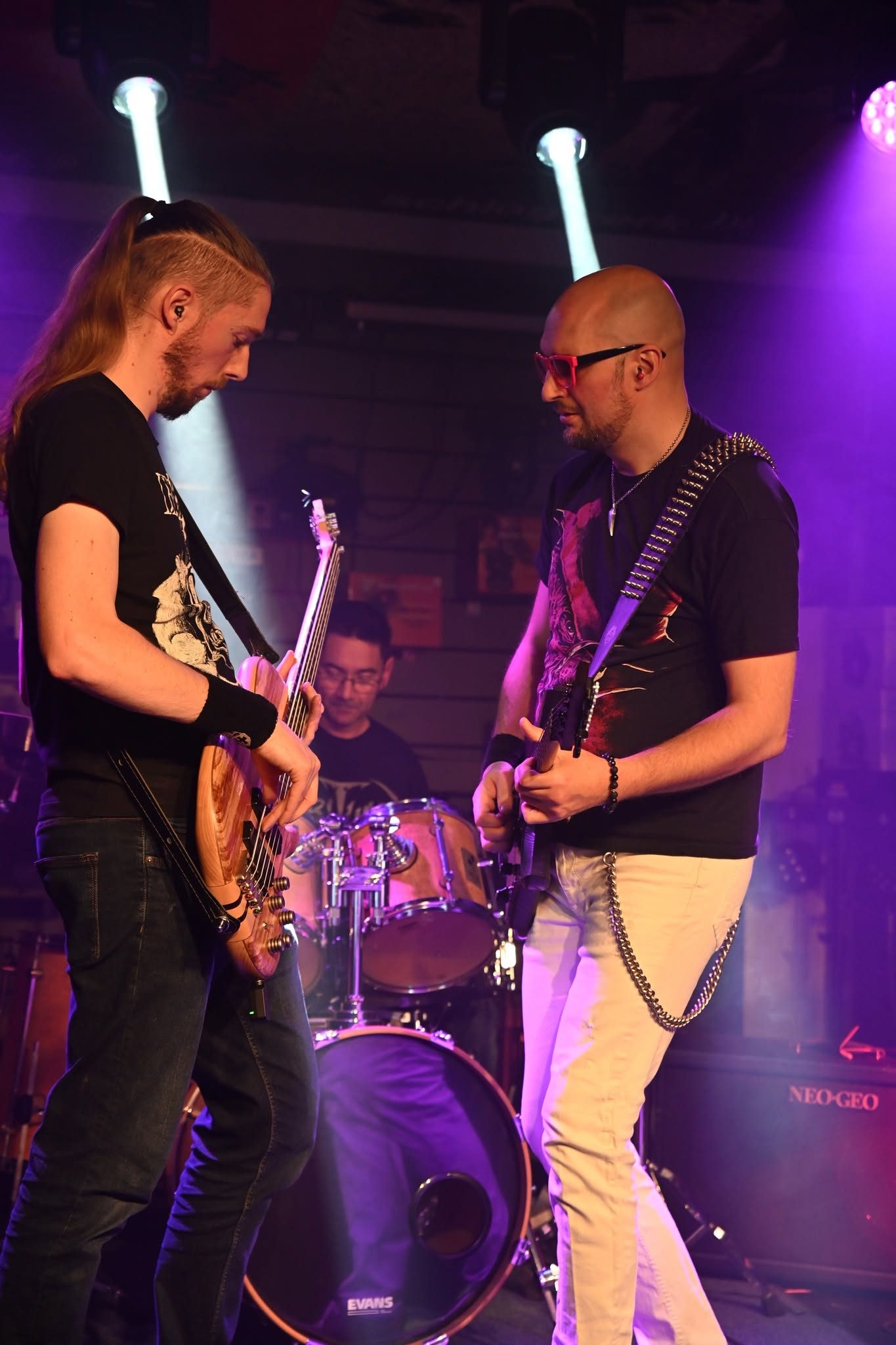 Le bassiste et le guitariste de 83FM jouent ensemble, le batteur derrière eux